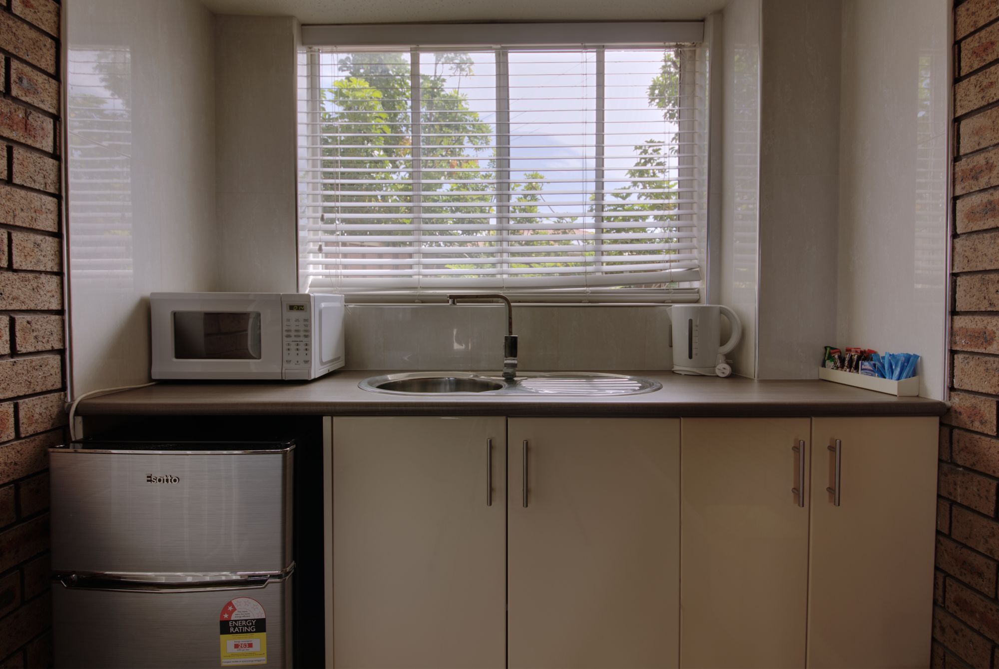 Eine kleine Küche mit Mikrowelle, Wasserkocher und Kühlschrank.