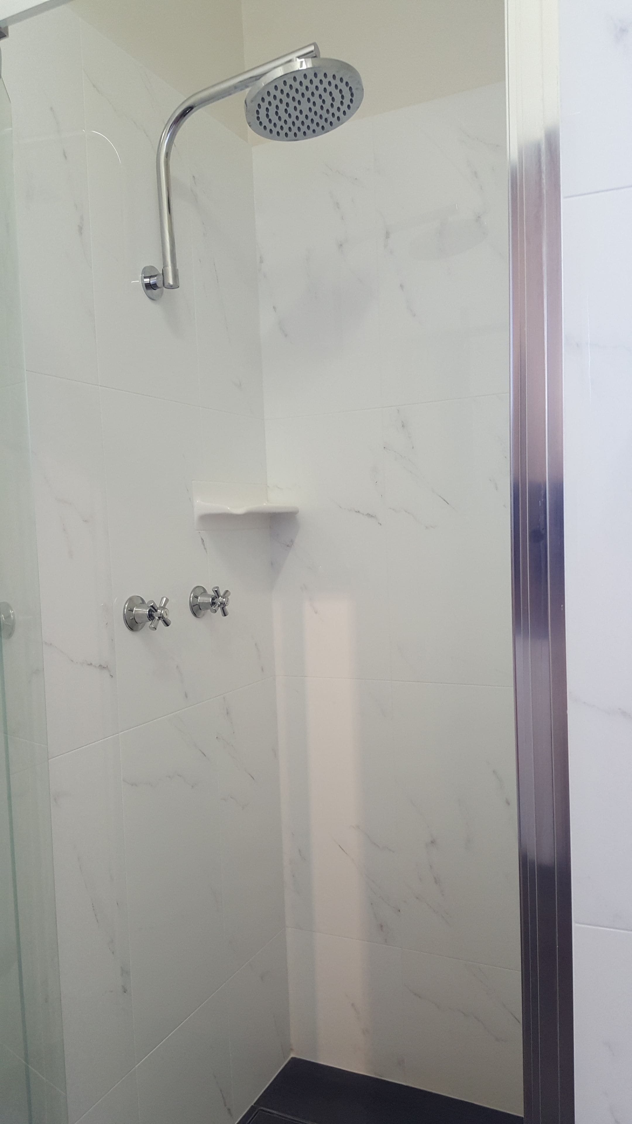 Et bruseområde med brusehoved, vandhane og kontrolpanel.