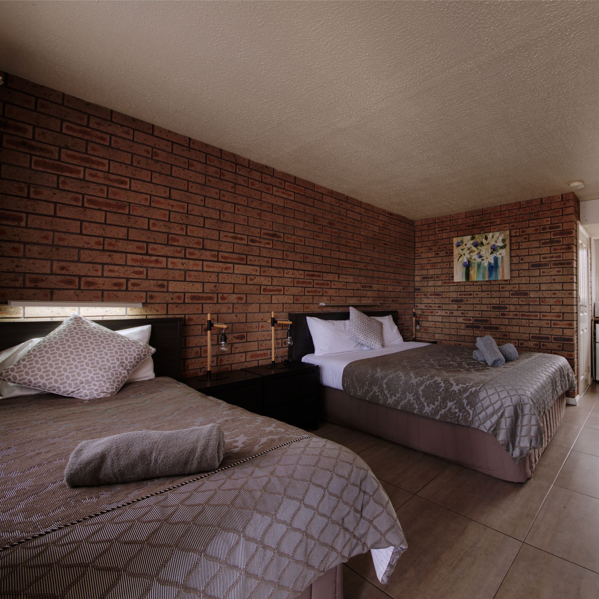 Ein Hotelzimmer mit zwei Betten, einer Ziegelwand und einem Gemälde.