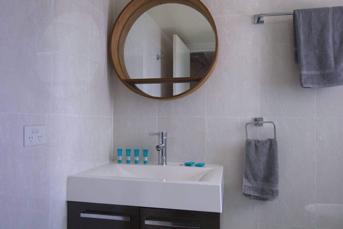 A bathroom with a white sink, a mirror, and a towel rack.