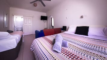 Et hotelværelse med to senge, en ventilator, et fjernsyn og en dør til badeværelset.