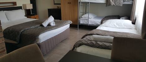 Een hotelkamer met een eenpersoonsbed, een slaapbank, een bureau en een stapelbed.