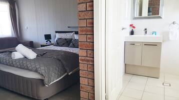 A bedroom with a bed, a nightstand, a lamp, and a brick wall.