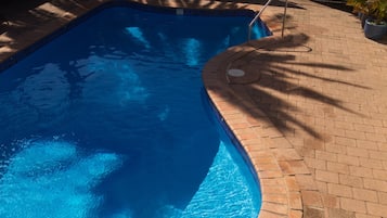 Una piscina al aire libre, sillones reclinables de piscina