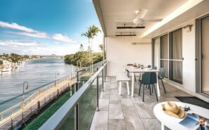 Un balcone con vista su un fiume, un tavolo da pranzo con sedie e una ventola a soffitto.