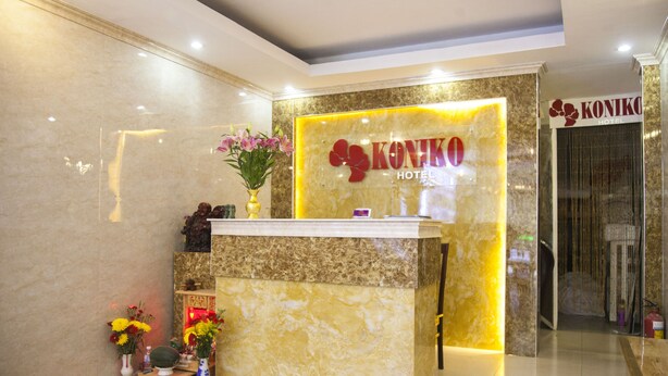 A reception desk with a marble counter, a vase with flowers, and a sign for Koniko Hotel. - Koniko hotel (Ho Chi Minh City)