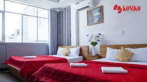 A hotel room with two beds, red bedding, a painting on the wall, and a window with curtains. - Koniko hotel (Ho Chi Minh City)