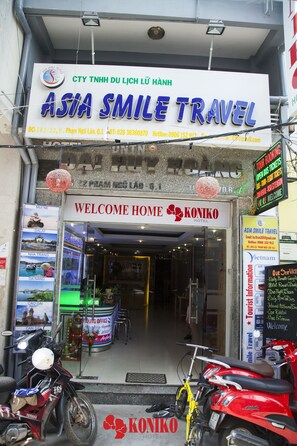 Een hotelingang met een bord voor Asia Smile Travel en een welkomstbord voor Koniko Hotel.