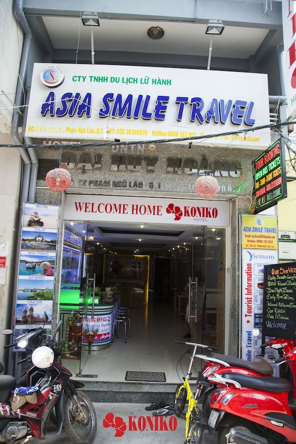 A hotel entrance with a sign for Asia Smile Travel and a welcome sign for Koniko Hotel.