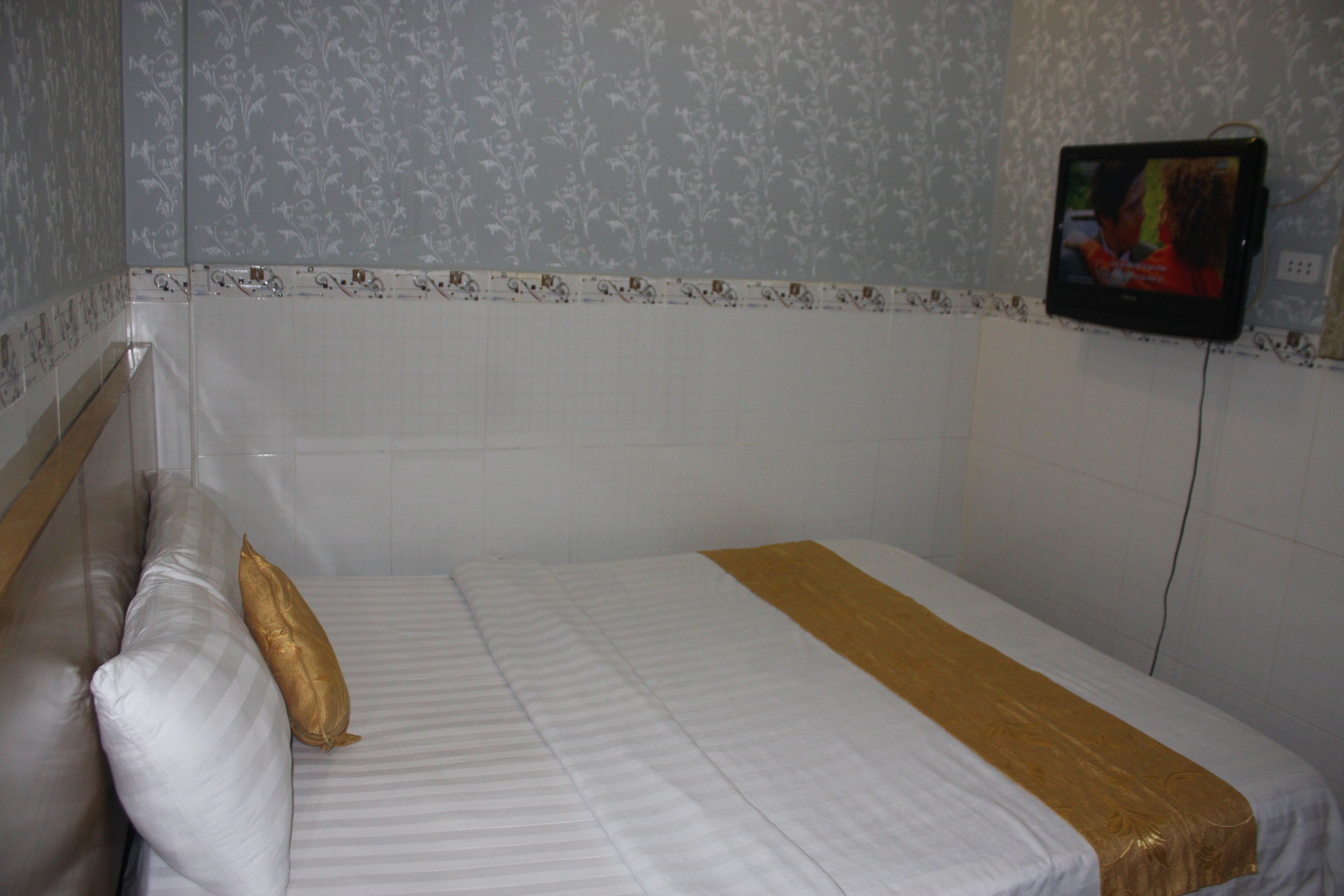 A hotel room with a bed, a TV mounted on the wall, and a patterned wallpaper.