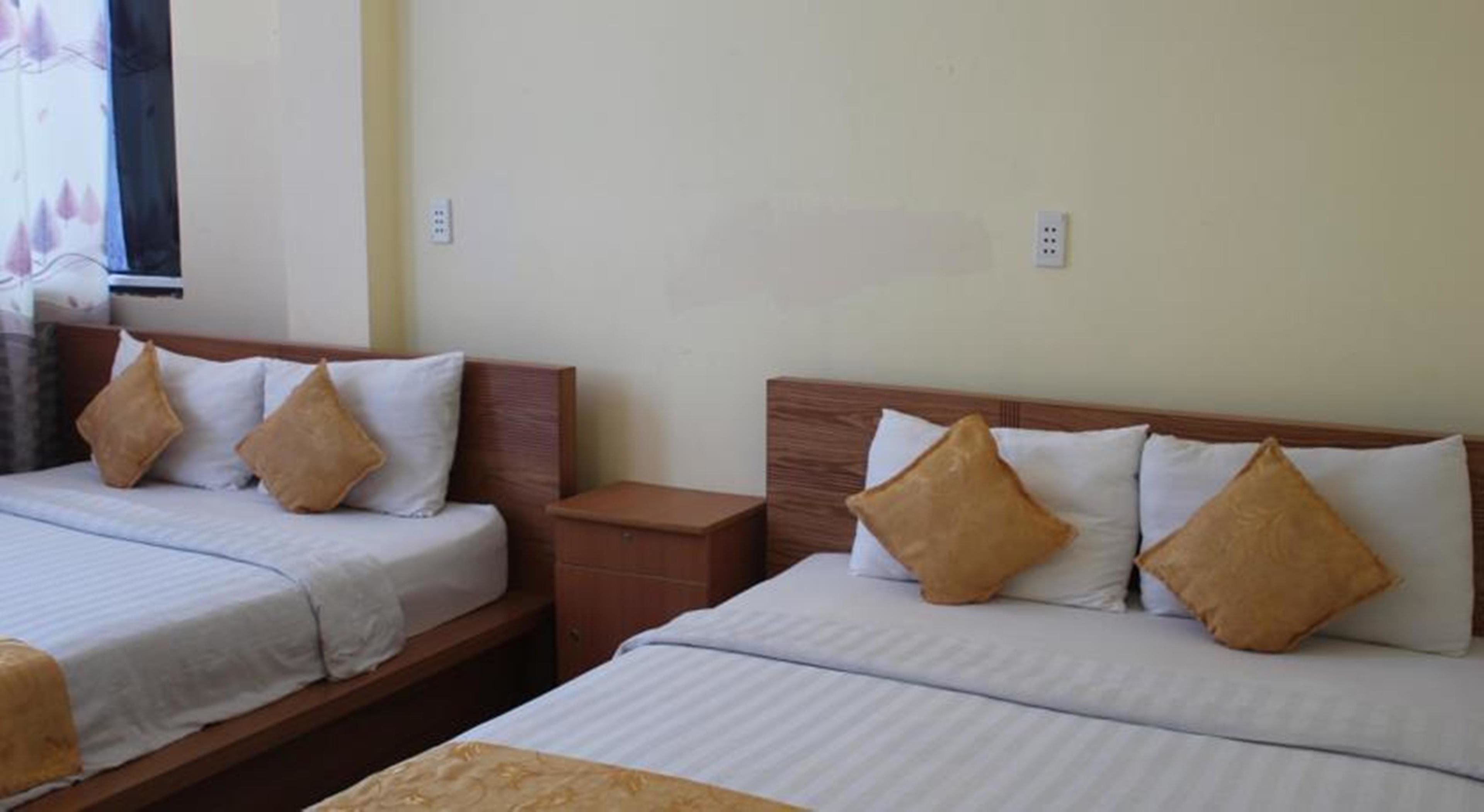 Two single beds with wooden headboards and white bedding, each with a brown pillow.