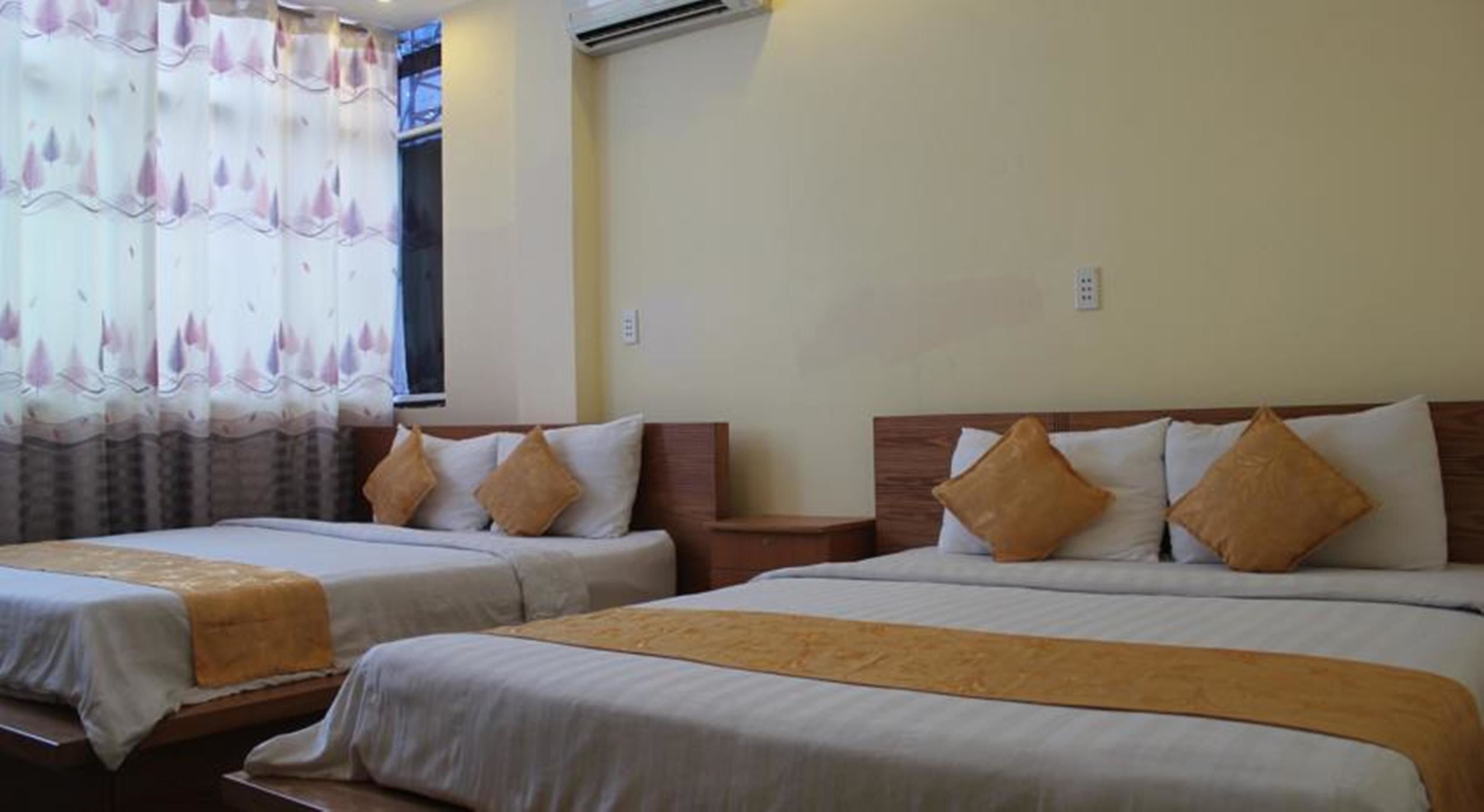 A hotel room with two single beds, each with a wooden headboard and white bedding.