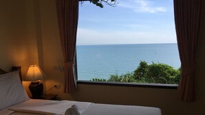 Una habitación de hotel con cama, lámpara y vista al mar a través de una ventana.