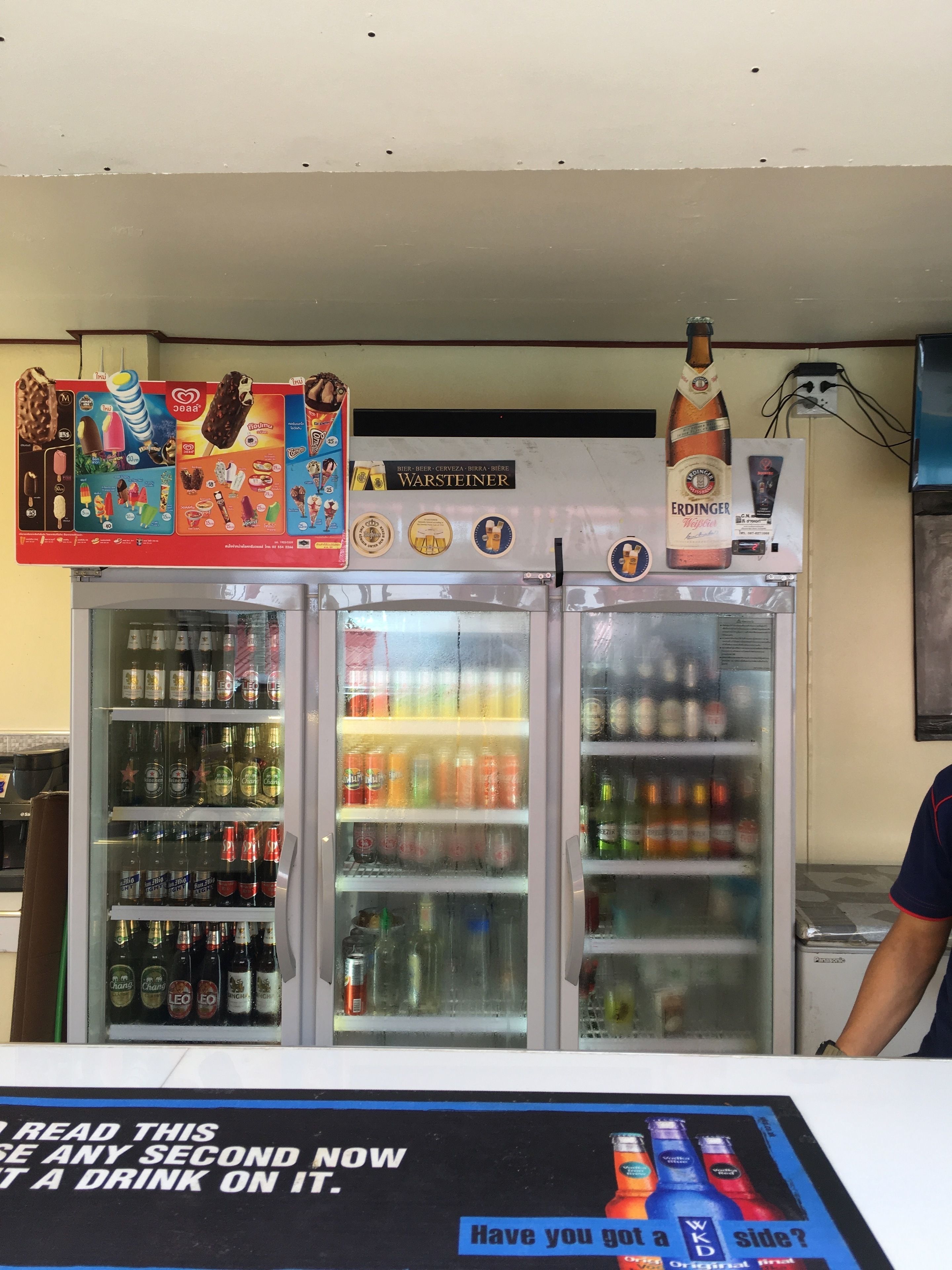 Un dispensador de bebidas con un cartel encima y un póster debajo.