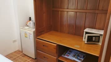 Una kitchenette compacta con refrigerador, microondas y un mueble de almacenamiento de madera.