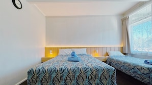A hotel room with two beds, each with patterned bedding and a headboard. There is a clock on the wall and a window with curtains. - Seymour Motel (Seymour)