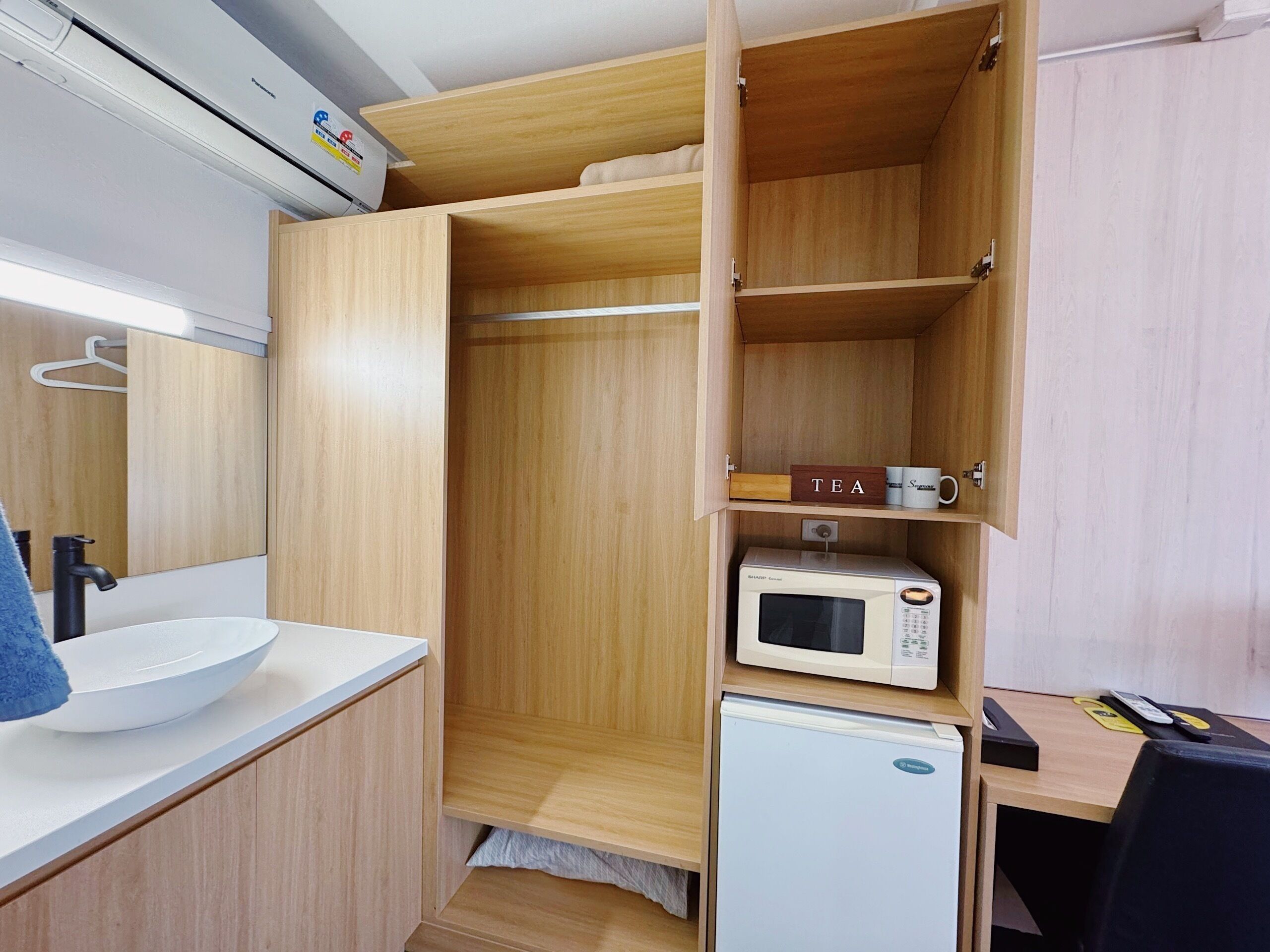 A compact kitchenette with a white sink, a microwave, and a small refrigerator.
