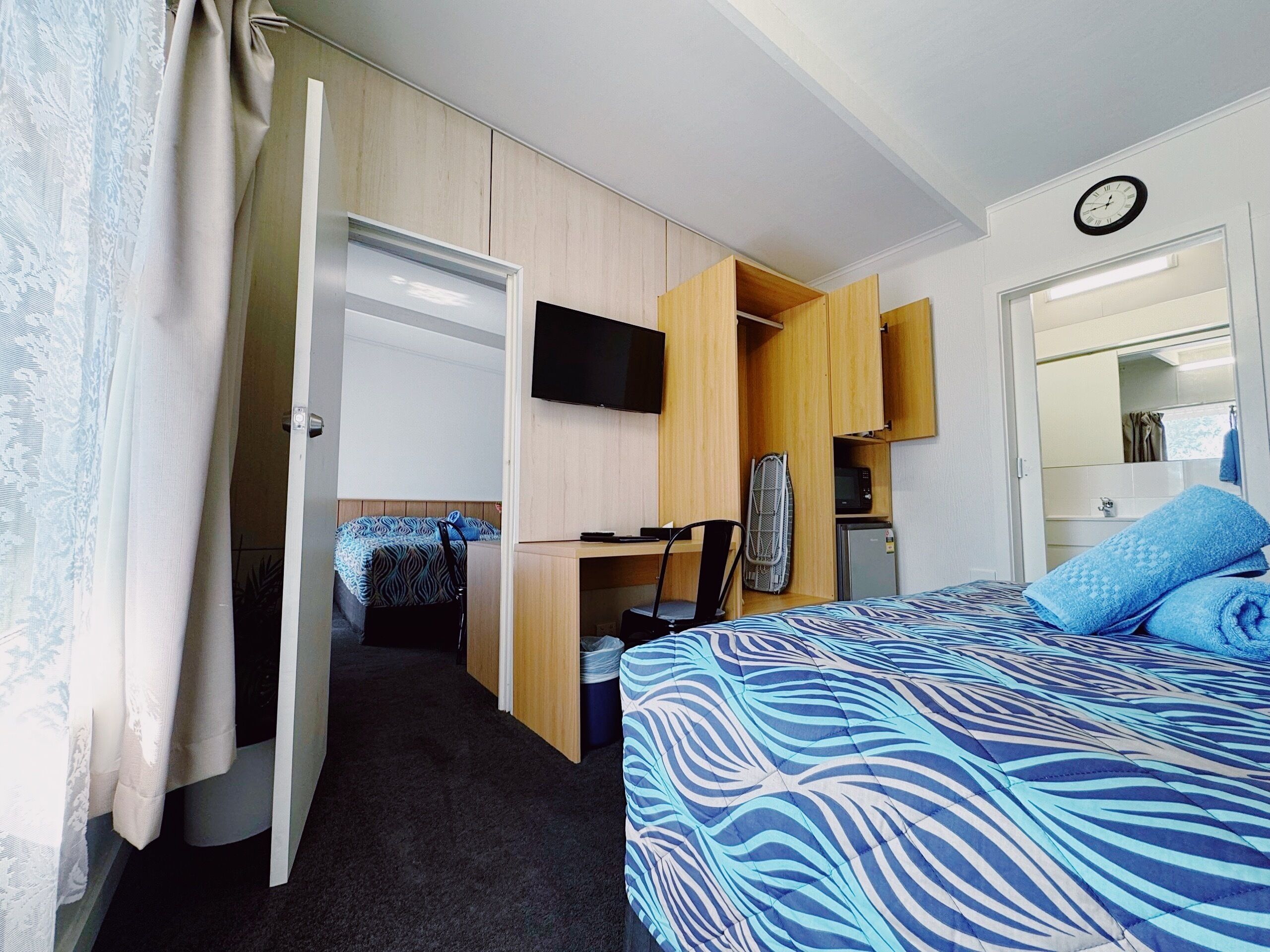 Een kleine hotelkamer met een bed, bureau, televisie en garderobe.