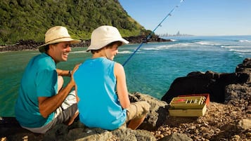 Two people sitting on rocks by the sea, fishing.