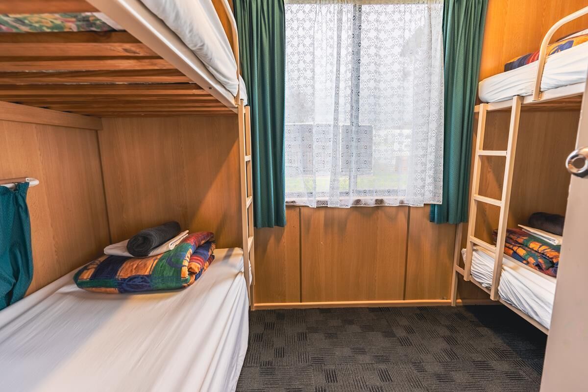 Habitación con literas, una ventana, una puerta de madera y piso alfombrado.