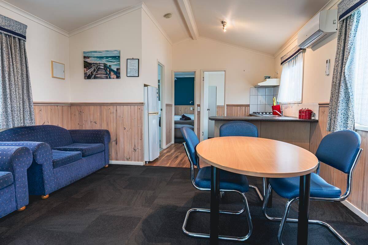 Un espacio habitable pequeño con un sofá, una mesa redonda y un rincón de cocina.