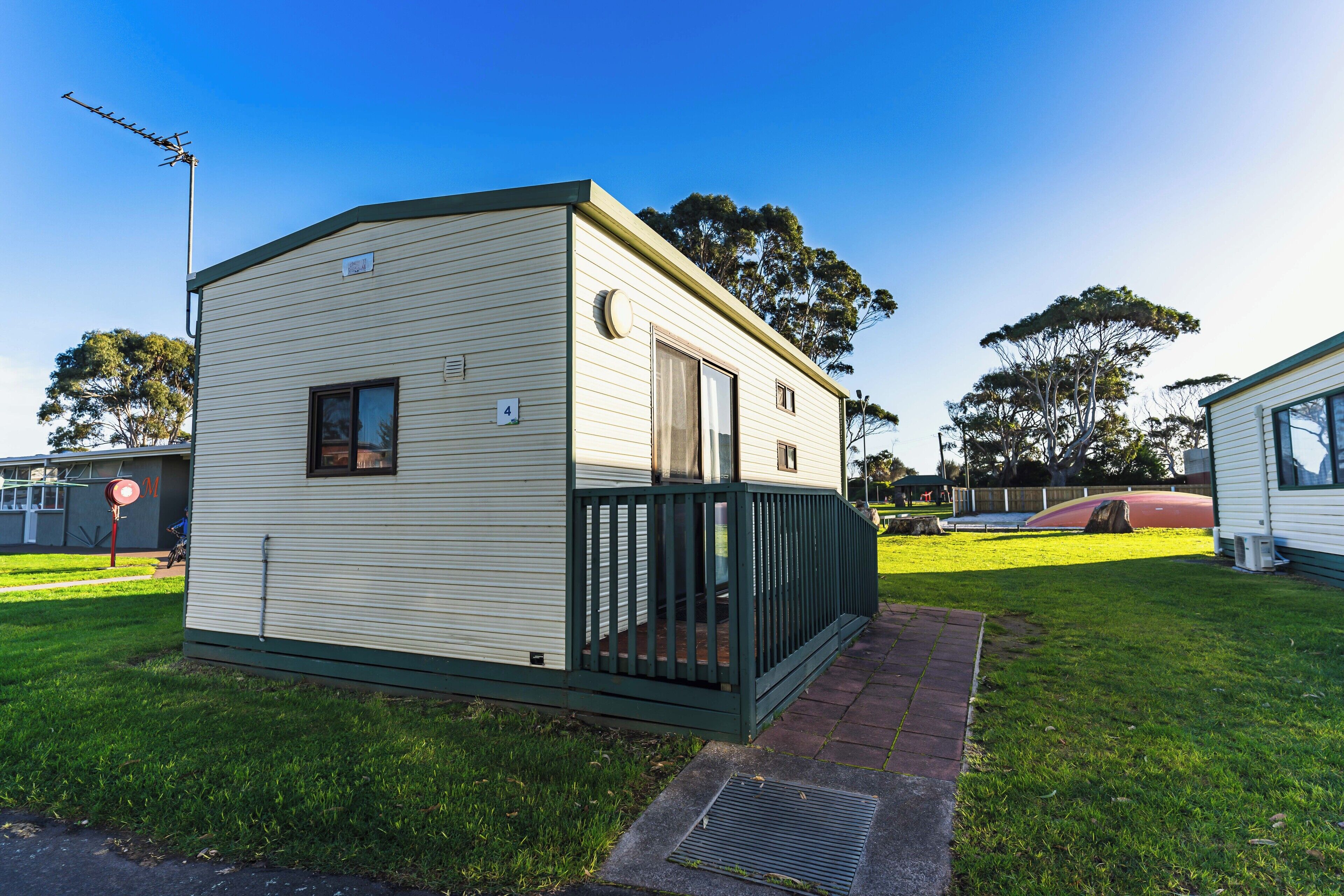 A small, single-story mobile home with a fenced porch and a window.