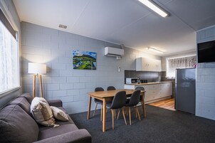 Un espacio habitable compacto con comedor, kitchenette y un sofá con cojines.