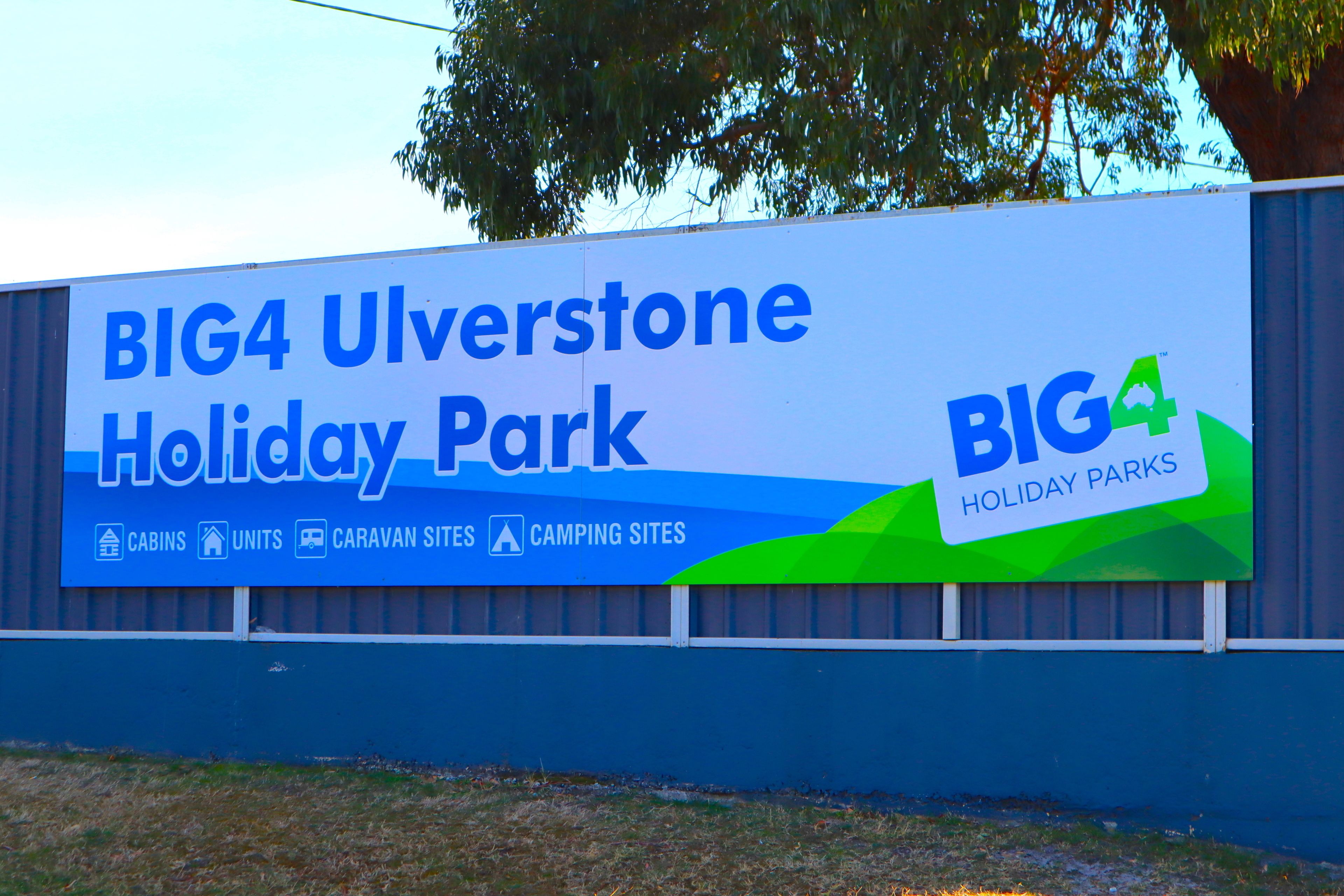 A billboard advertising BIG4 Ulverstone Holiday Park, highlighting amenities such as cabins, units, caravan sites, and camping sites.