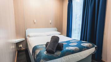 A hotel room with a bed, a nightstand, and a window with curtains.