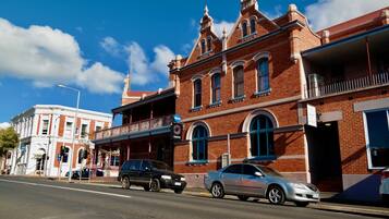 A street view with a red brick building featuring a balcony and a sign for 'Joasis'.