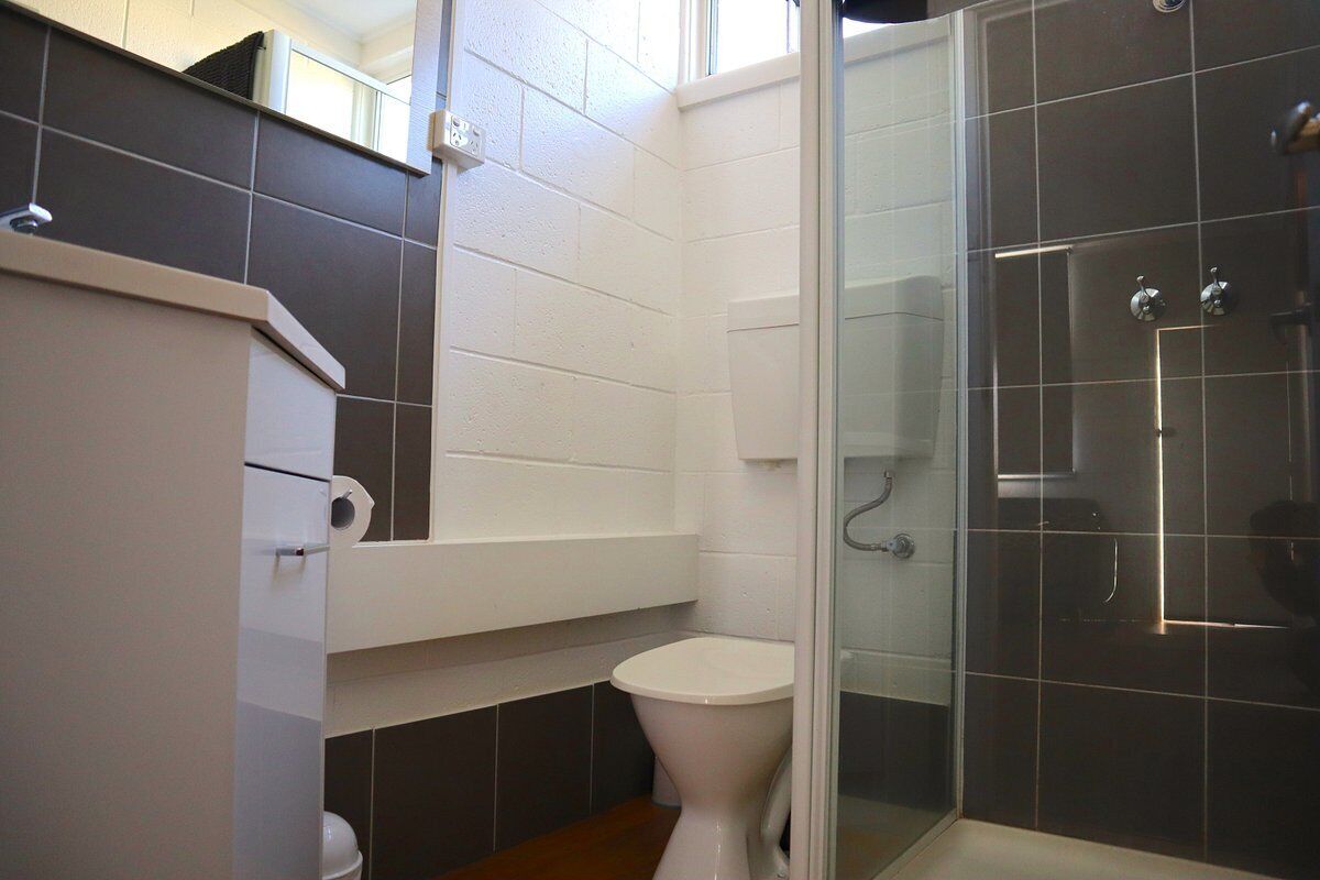 A bathroom with a toilet, a shower enclosure, and a white sink.