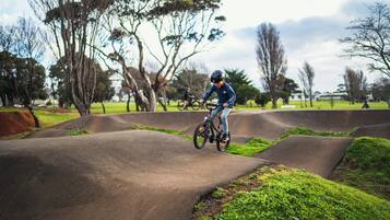 A person riding a bicycle on a concrete track surrounded by grass and trees.