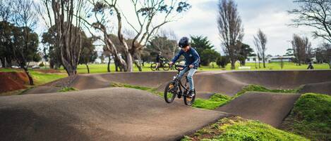 A person riding a bicycle on a concrete track surrounded by grass and trees.
