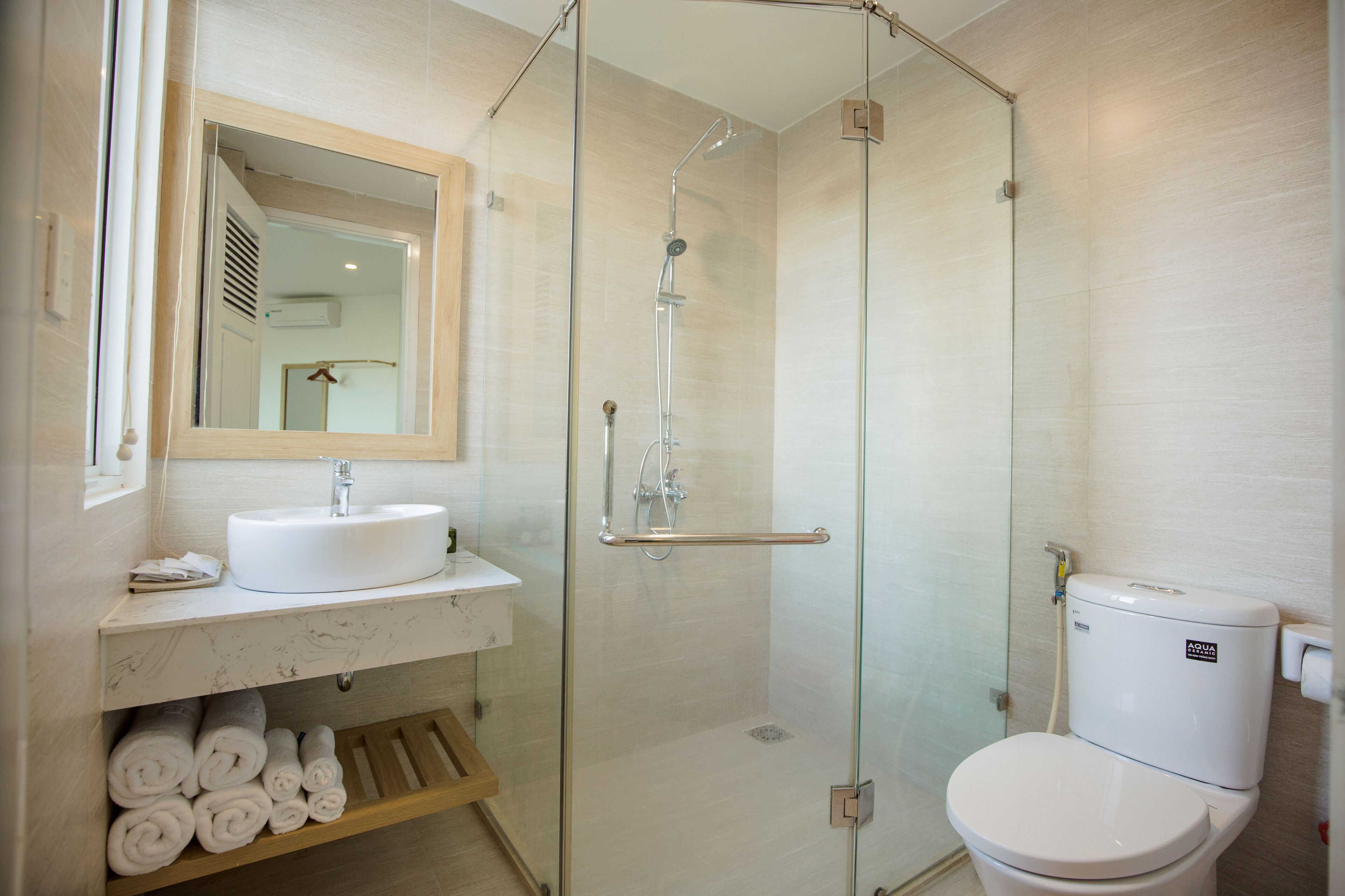 A modern bathroom with a glass-enclosed shower, a white sink, and a toilet.