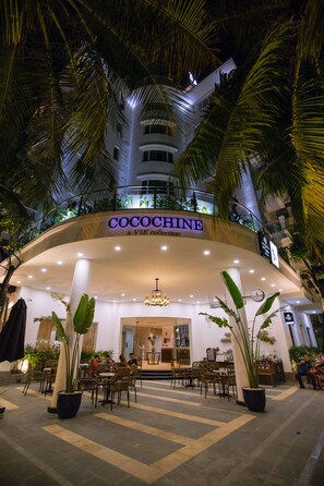A hotel entrance with a sign reading "COCOCHINE a VIE collection," surrounded by potted plants and outdoor seating. - Cocochine - a VIE collection (Da Nang)