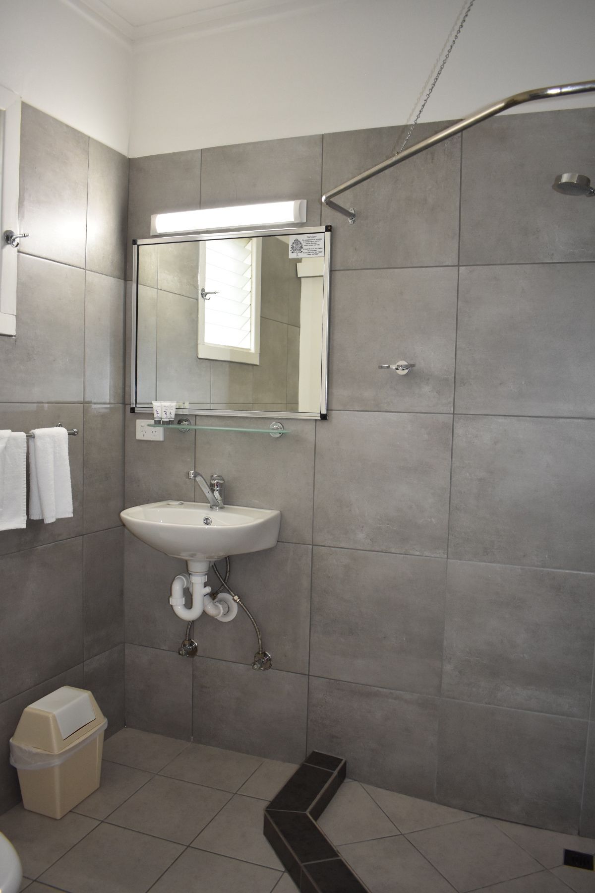 A modern bathroom with a white sink, mirror, and shower.