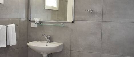 A modern bathroom with a white sink, mirror, and shower.