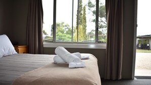A hotel room with a bed, a window with curtains, and a view of the outside.
