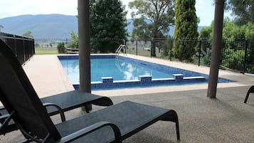 Una piscina al aire libre, sillones reclinables de piscina
