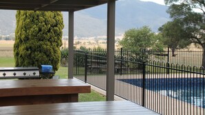A covered outdoor area with a barbecue grill, a pool, and a view of distant mountains.