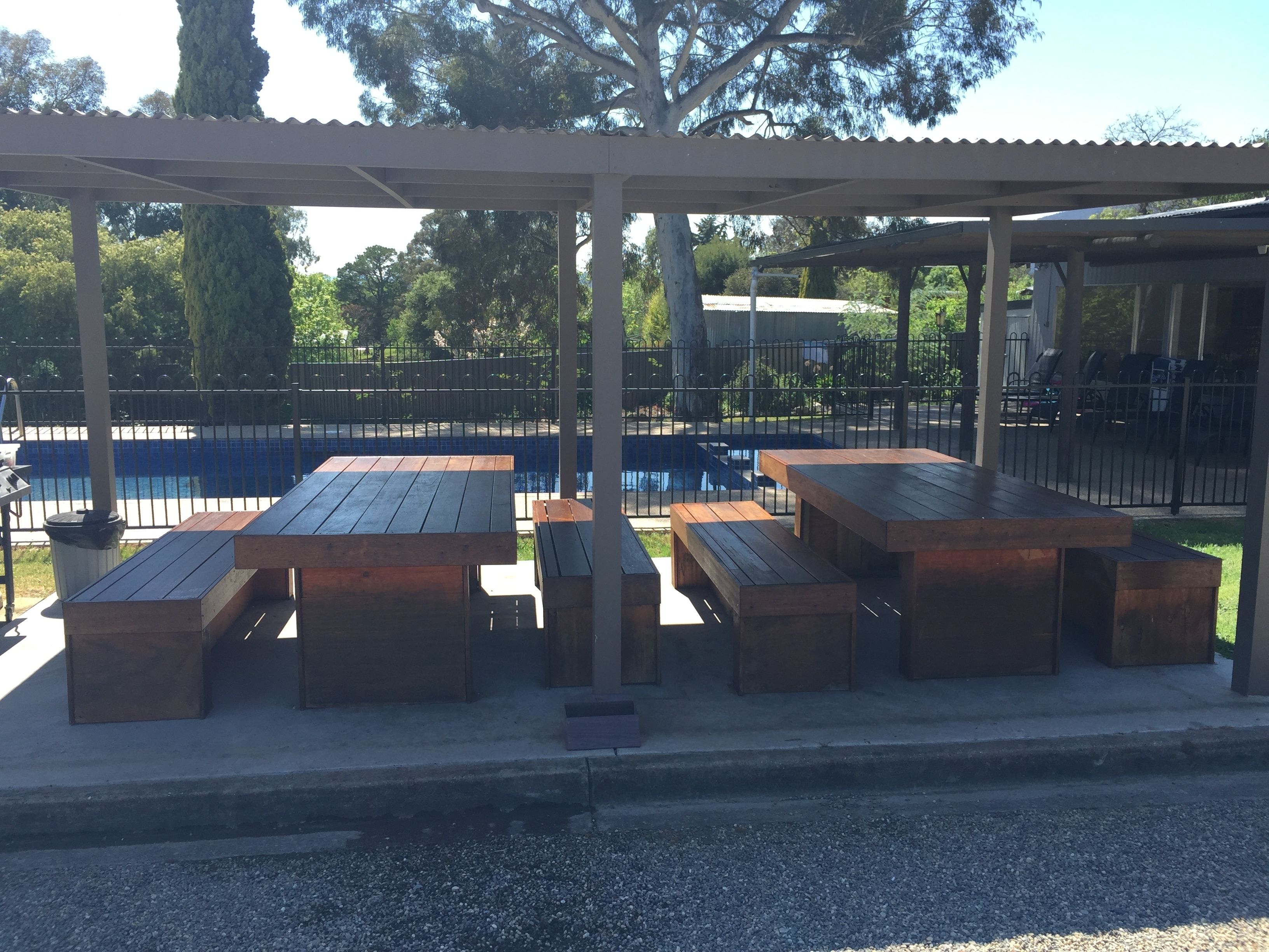 An outdoor seating area with wooden tables and benches under a covered structure.