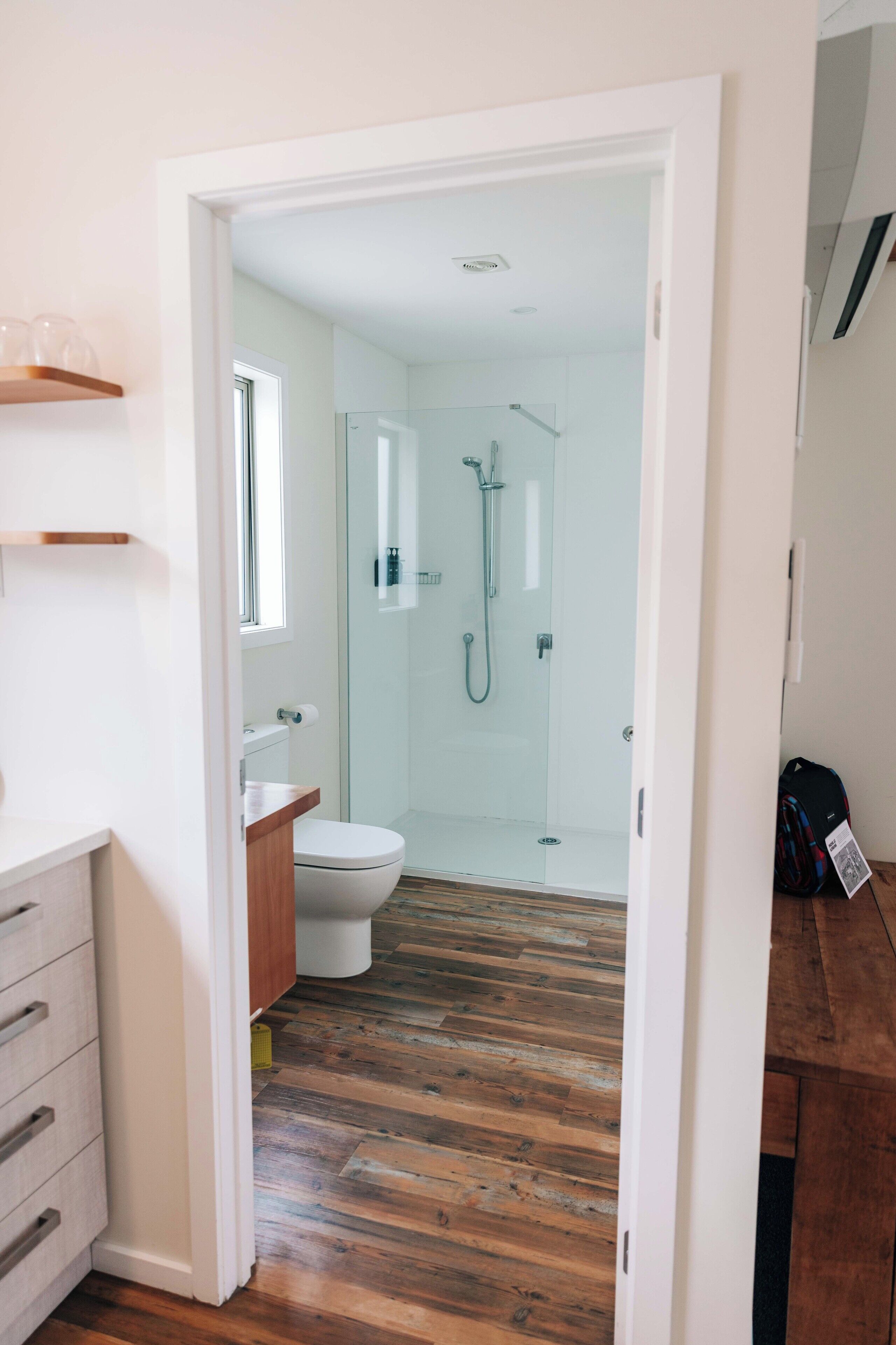 Un baño moderno con cabina de ducha de vidrio, inodoro y tocador de madera.