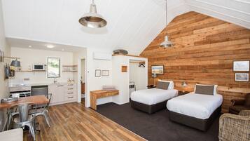 A compact room with two beds, a dining area, and a kitchenette.