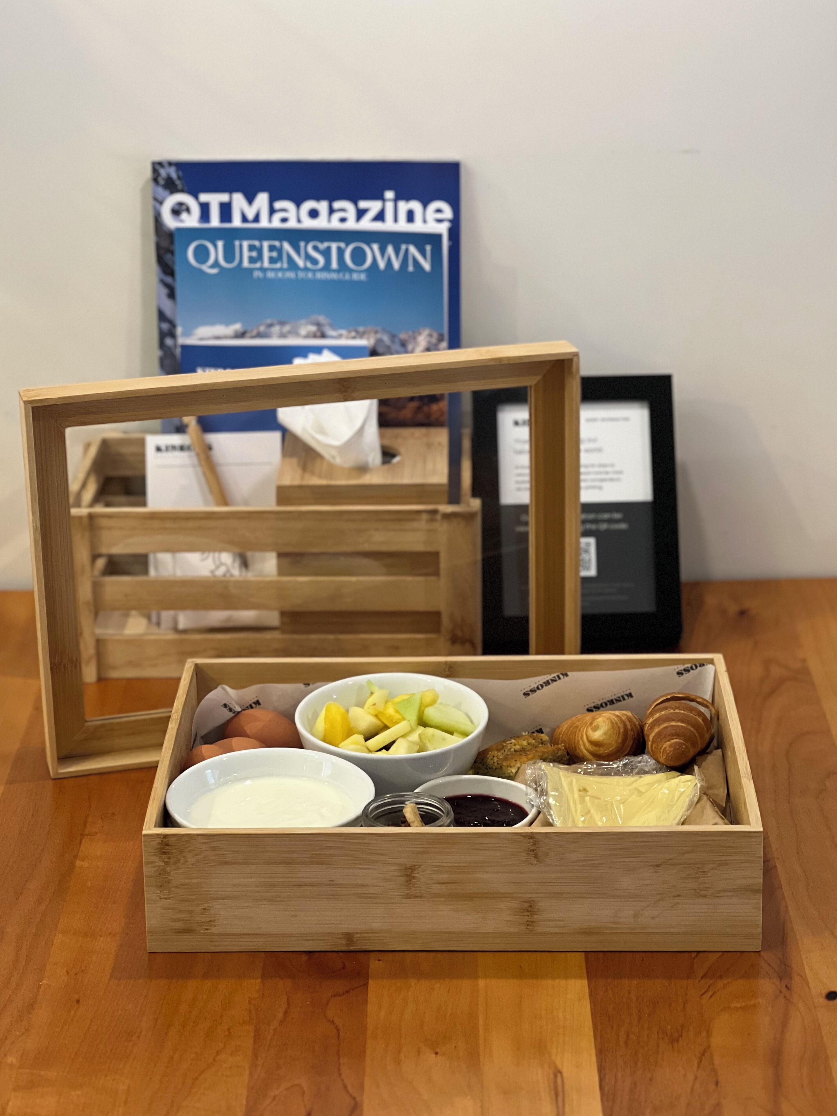 A wooden crate with a variety of food items including apples, cheese, and pastries.