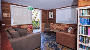 A cozy reading area with two sofas, a small table, and a bookshelf. - Cairns City Backpackers Hostel (Parramatta Park)