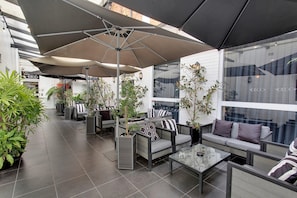Un espace extérieur aménagé avec des meubles modernes, de grands parasols et des plantes en pot.