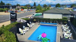 A swimming pool with lounge chairs and a view of the surrounding area. - Little Haven (Taupo)