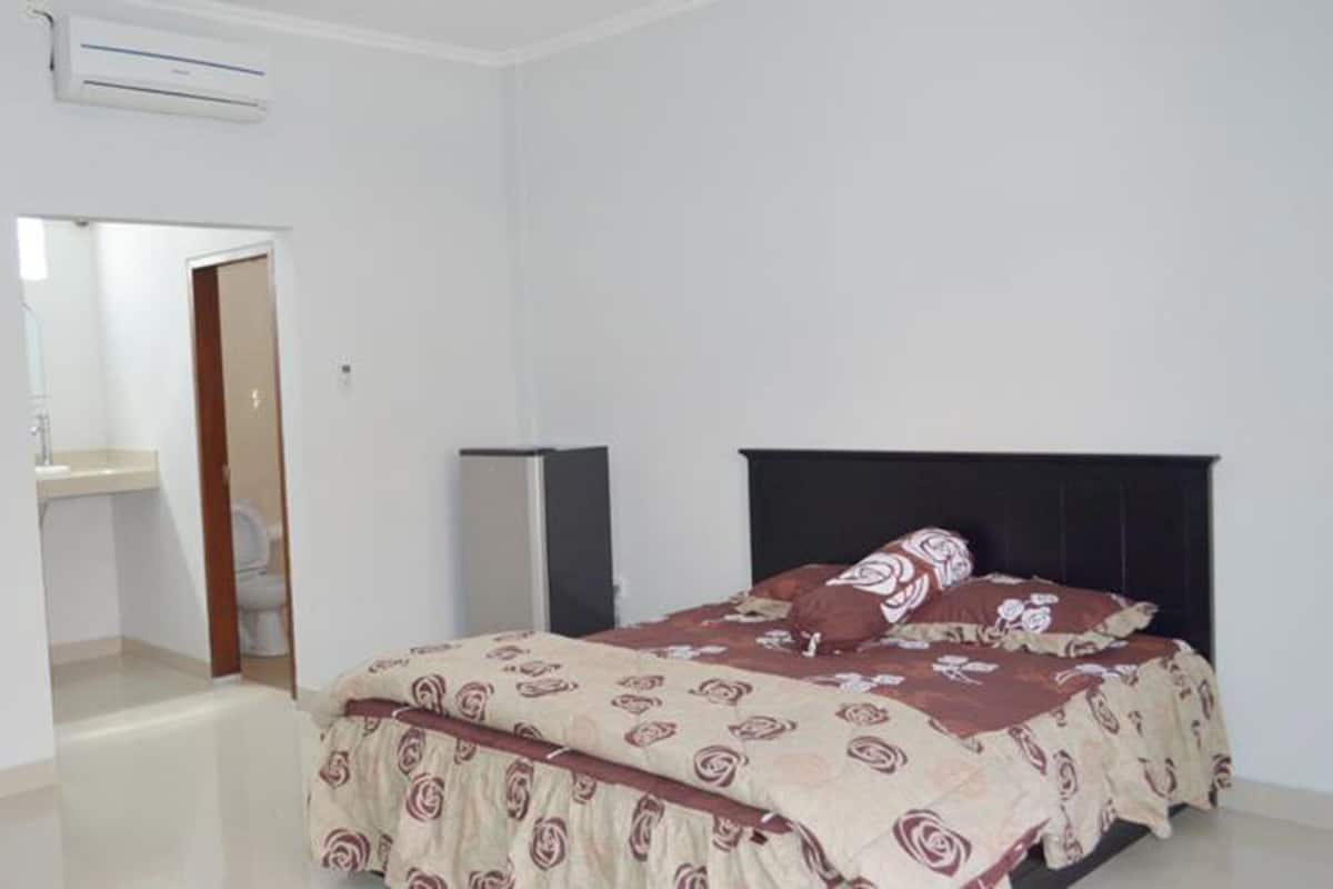 Une chambre à coucher comprenant un lit, une table de chevet, une armoire et un appareil de climatisation.