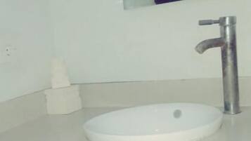 A bathroom with a white sink, a mirror, and a towel dispenser.