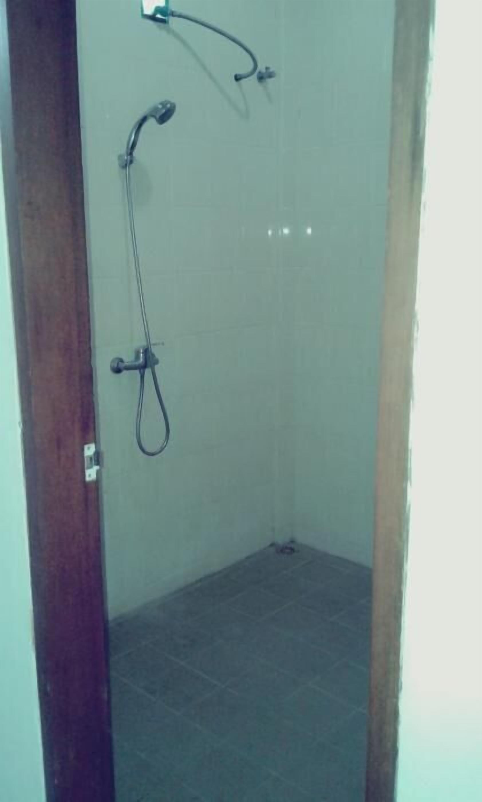 A small, enclosed shower area with a tiled floor and a wooden door frame.